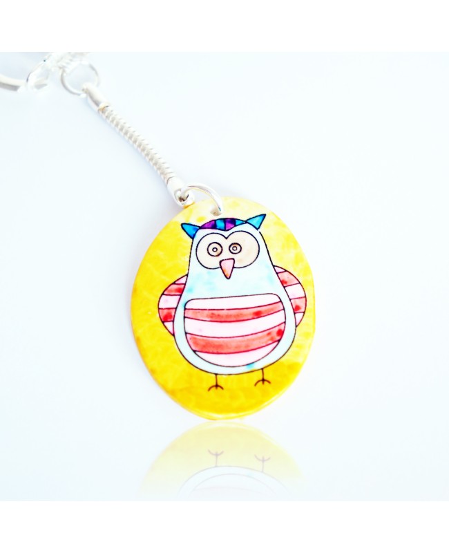 Blue and red owl keychain on a yellow background