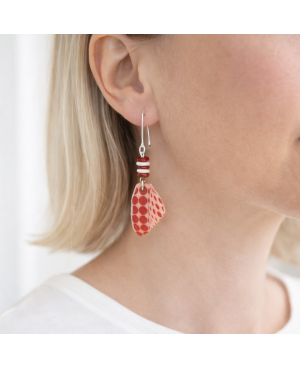White dangling earrings with red polka dots being worn